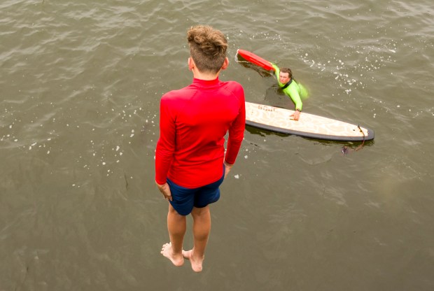 A junior lifeguard jumps off the San Clemente Pier as...
