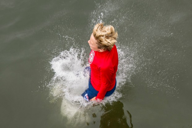 A junior lifeguard breaks the water after jumping off the...